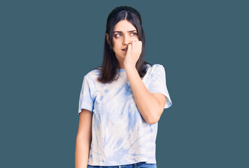 Young beautiful girl wearing casual t shirt looking stressed and nervous with hands on mouth biting nails. anxiety problem.