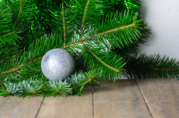 Spruce branches with green needles and Christmas balls on a wooden background.
