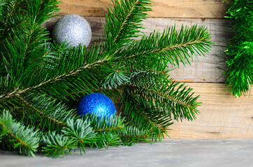 Spruce branches with green needles and Christmas balls on a wooden background.