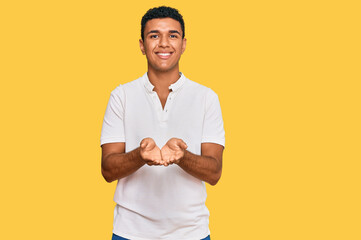 Young arab man wearing casual clothes smiling with hands palms together receiving or giving gesture. hold and protection