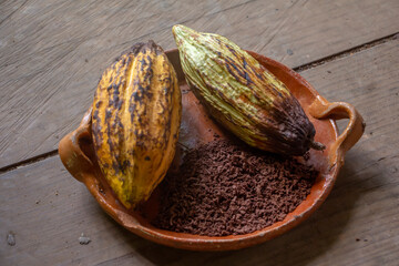 Vainas de cacao molido sobre bandeja de barro sobre mesa de madera chocolate