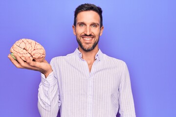 Young handsome man asking for care memory holding brain over isolated purple background looking...