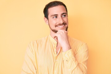 Young handsome man wearing casual clothes with hand on chin thinking about question, pensive expression. smiling with thoughtful face. doubt concept.