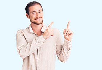 Young handsome caucasian man wearing casual clothes smiling and looking at the camera pointing with two hands and fingers to the side.