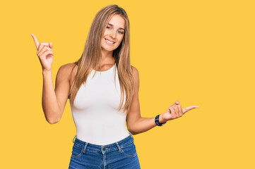 Young blonde woman wearing casual style with sleeveless shirt smiling confident pointing with fingers to different directions. copy space for advertisement
