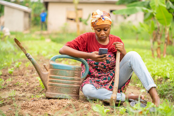  beautiful African lady with head scarf, plastic container-landscape image of Black woman in a...