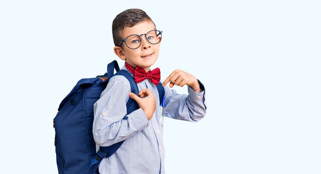 Cute blond kid wearing nerd bow tie and backpack pointing finger to one self smiling happy and proud