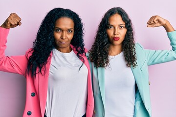 African american mother and daughter wearing business style strong person showing arm muscle, confident and proud of power