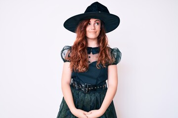 Young beautiful woman wearing witch halloween costume smiling looking to the side and staring away thinking.