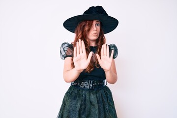 Young beautiful woman wearing witch halloween costume moving away hands palms showing refusal and denial with afraid and disgusting expression. stop and forbidden.