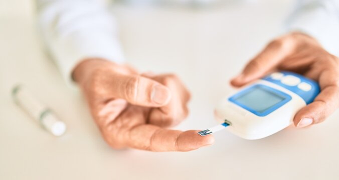 Close Up Of Man With Diabetes Using Insuline Glucometer With Blood From The Finger