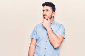 Young hispanic man wearing casual clothes thinking concentrated about doubt with finger on chin and looking up wondering