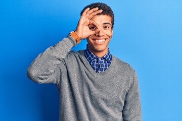 Young african amercian man wearing casual clothes smiling happy doing ok sign with hand on eye looking through fingers