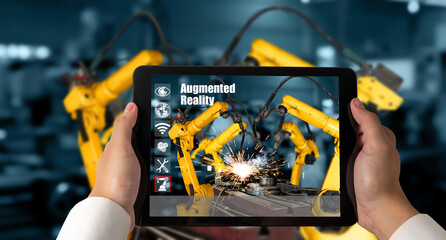 Engineer controls robotic arms by augmented reality industry technology application software. Smart robot machine in future factory working in concept of Industry 4.0 or 4th industrial revolution.