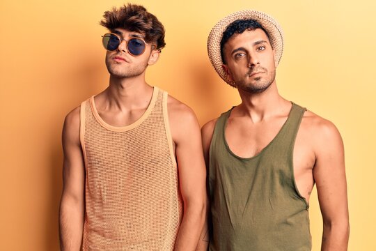 Young gay couple wearing summer clothes relaxed with serious expression on face. simple and natural looking at the camera.