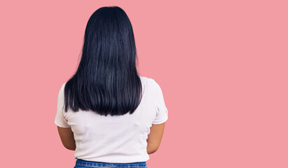 Young beautiful asian girl wearing casual clothes and glasses standing backwards looking away with...