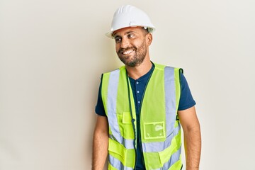 Handsome man with beard wearing safety helmet and reflective jacket looking to side, relax profile...