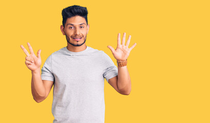 Handsome latin american young man wearing casual tshirt showing and pointing up with fingers number eight while smiling confident and happy.