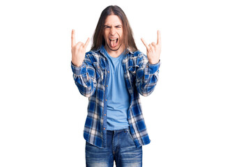 Young adult man with long hair wearing casual shirt shouting with crazy expression doing rock symbol with hands up. music star. heavy concept.