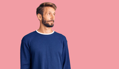 Handsome blond man with beard wearing casual sweater smiling looking to the side and staring away thinking.