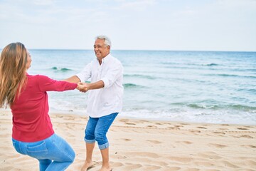 Middle age couple in love dancing at the beach happy and cheerful together