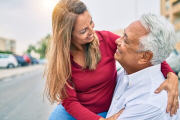 Fototapeta premium Middle age hispanic couple smiling happy and hugging sitting on the bench.