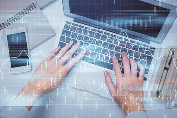 Double exposure of woman hands working on computer and forex graph hologram drawing. Top View. Financial analysis concept.