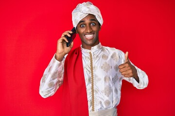 Indian man wearing tradition sherwani saree clothes speaking on the phone smiling happy and...