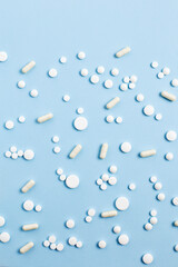 a pattern of white and red pills and capsules on a blue background. flat lay, top view