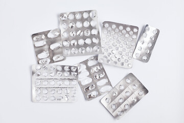 empty blister packs of pills with one partially full pack on white background. flat lay simple composition, top view