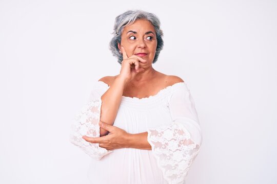 Senior hispanic grey- haired woman wearing casual clothes with hand on chin thinking about question, pensive expression. smiling with thoughtful face. doubt concept.