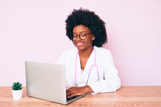 Young african american woman wearing doctor stethoscope working using computer laptop looking positive and happy standing and smiling with a confident smile showing teeth