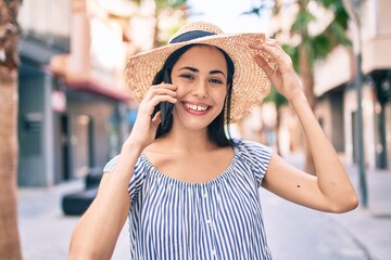 Young latin tourist girl on vacation smiling happy  talking on the smartphone at the city.