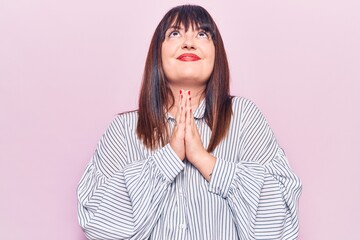 Young plus size woman wearing casual clothes begging and praying with hands together with hope expression on face very emotional and worried. begging.