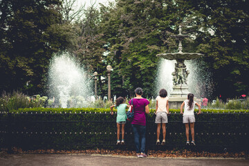 Children and mother enjoying the fountain in the park.