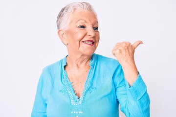 Senior beautiful woman with blue eyes and grey hair wearing summer clothes pointing thumb up to the side smiling happy with open mouth