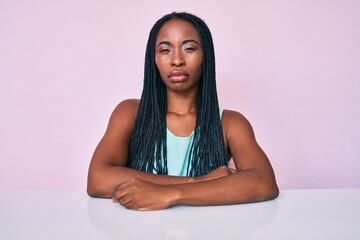 African american woman with braids wearing casual clothes sitting on the table skeptic and nervous, frowning upset because of problem. negative person.