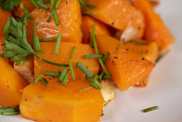 Delicious  roasted butternut squash spiced up with chives, close-up, healthy orange food concept,...