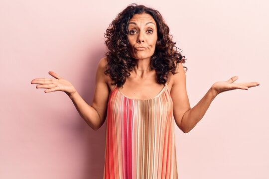 Middle age beautiful woman wearing casual t shirt clueless and confused with open arms, no idea and doubtful face.