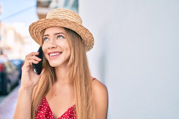 Young caucasian tourist girl smiling happy talking smartphone leaning on the wall.