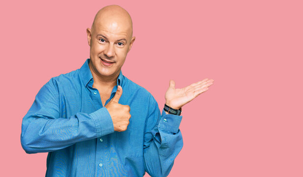 Middle age bald man wearing casual clothes showing palm hand and doing ok gesture with thumbs up, smiling happy and cheerful