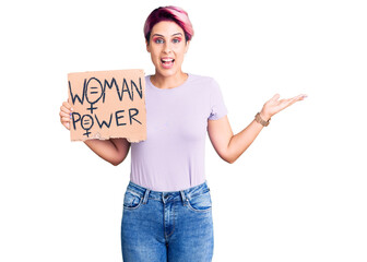 Young beautiful woman with pink hair holding woman power banner celebrating victory with happy smile and winner expression with raised hands