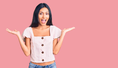 Young beautiful latin girl wearing casual clothes celebrating victory with happy smile and winner expression with raised hands