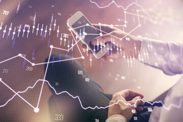 Double exposure of man's hands holding and using a digital device and forex graph drawing. Financial market concept.