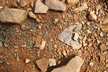 Wet ground, yellow soil, there are many small stones, details of the texture