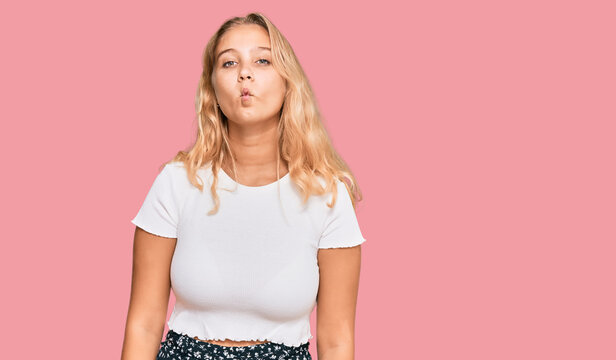 Young blonde girl wearing casual white tshirt making fish face with lips, crazy and comical gesture. funny expression.