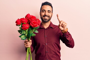 Young hispanic man holding flowers smiling with an idea or question pointing finger with happy face, number one