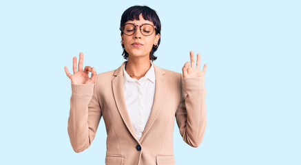 Young brunette woman with short hair wearing business jacket and glasses relax and smiling with eyes closed doing meditation gesture with fingers. yoga concept.