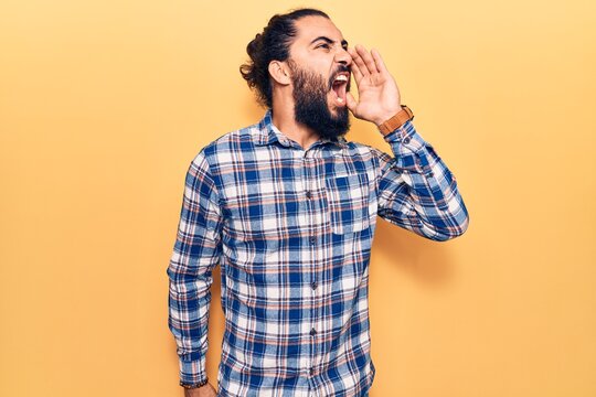 Young arab man wearing casual clothes shouting and screaming loud to side with hand on mouth. communication concept.