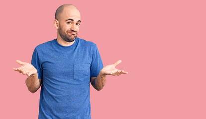 Young handsome man wearing casual t shirt clueless and confused expression with arms and hands...